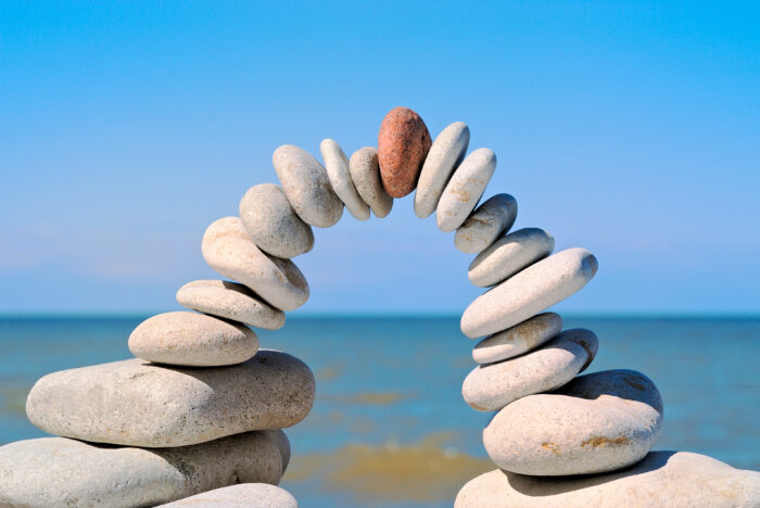 Stone arch with red stone at top in the morning on a beach